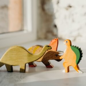 Charming wooden dinosaur toys placed on a surface, highlighted by gentle sunlight.